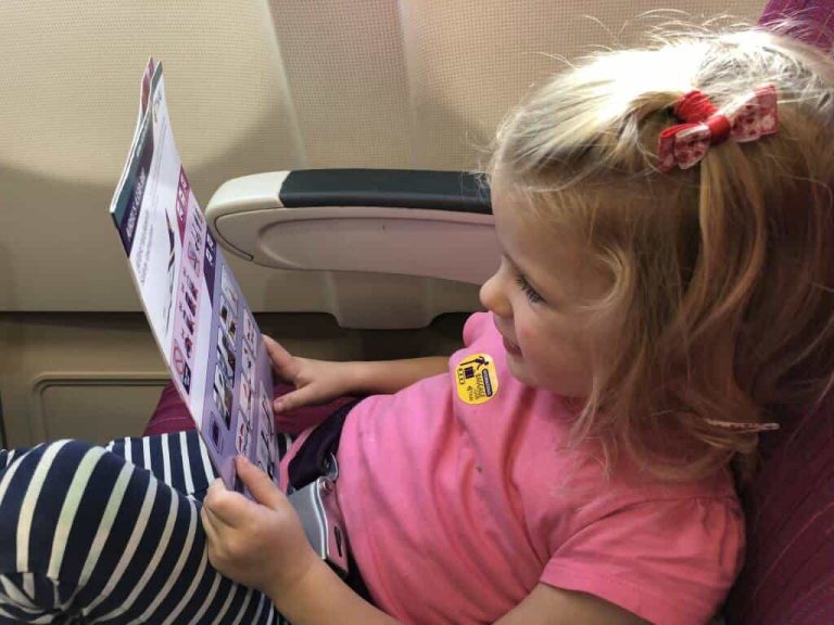 toddler on a plane reading safety card
